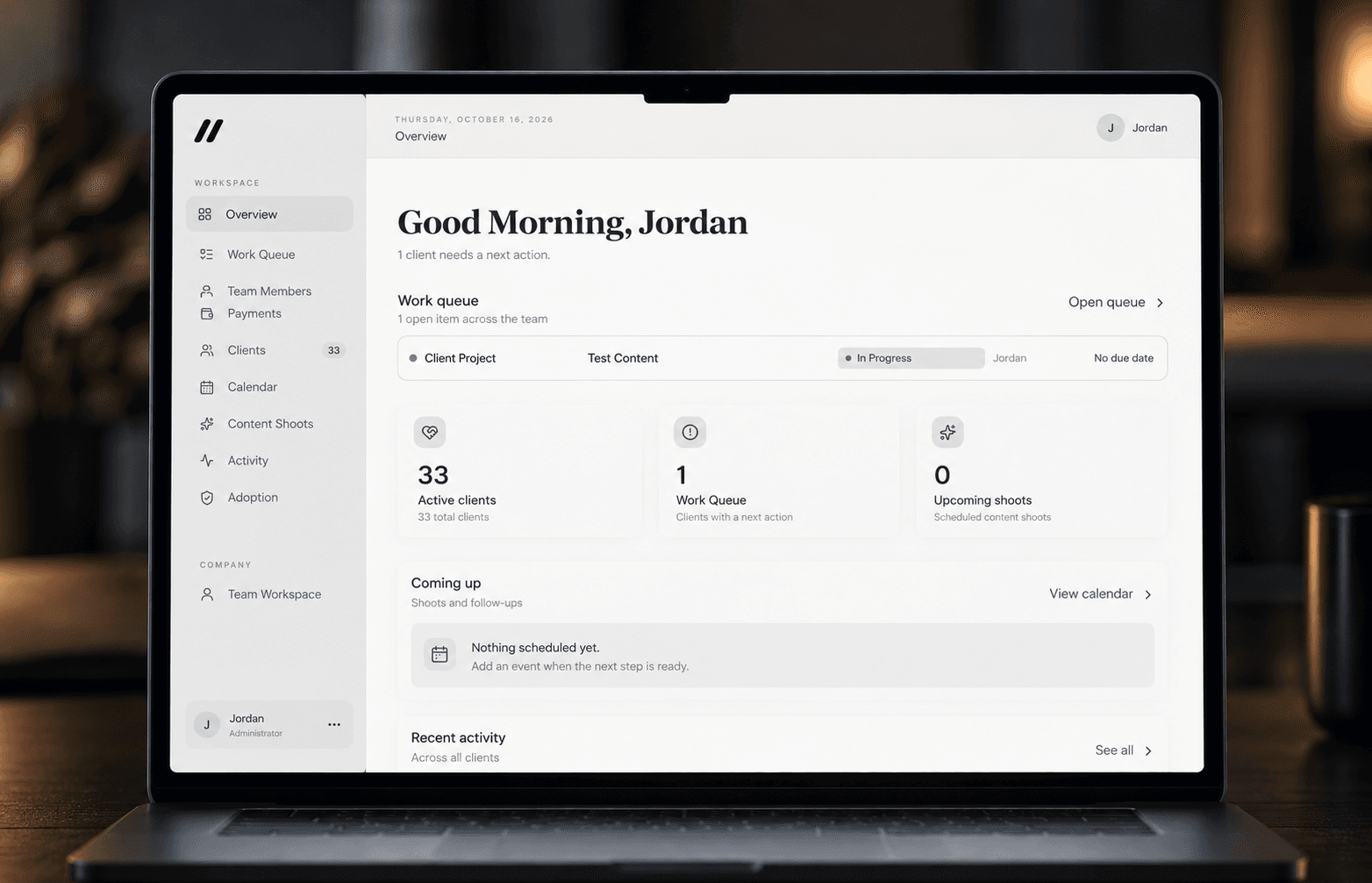 Laptop showing a social media agency dashboard with an overview, work queue, and client activity.